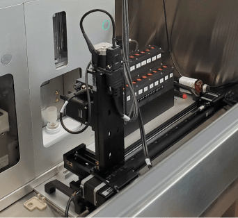 Photo of the automated sample-transfer hardware mounted on a Sony FACS cell sorter, including a robotic arm and sample rack.