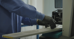 Gloved researcher operating lab automation equipment for high-throughput cell engineering.