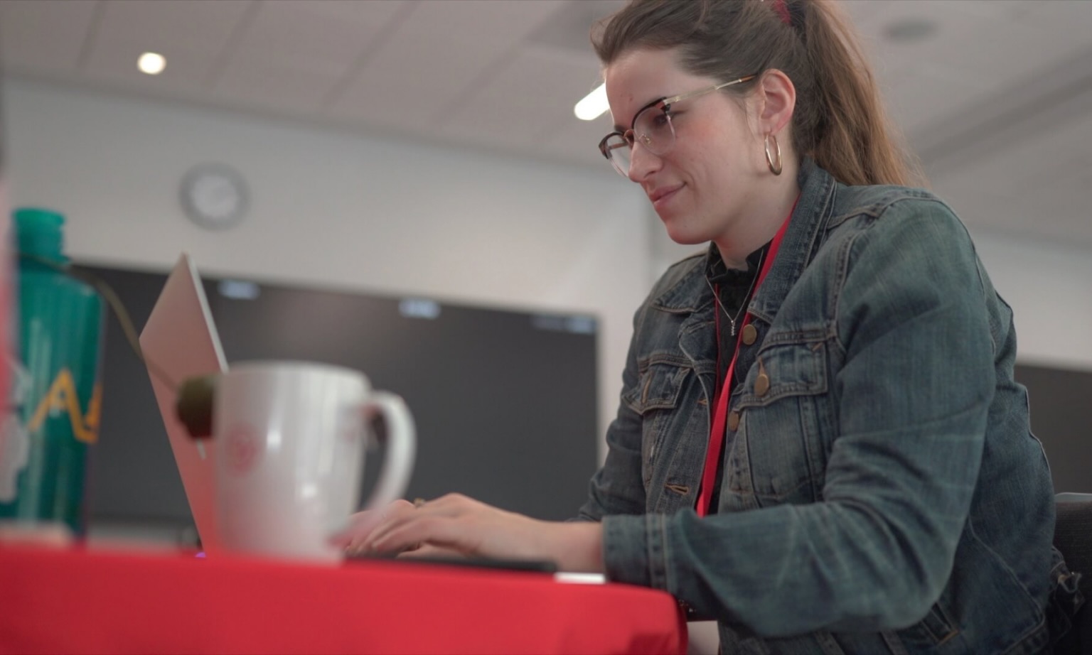A woman types on her laptop while sitting at a desk. 