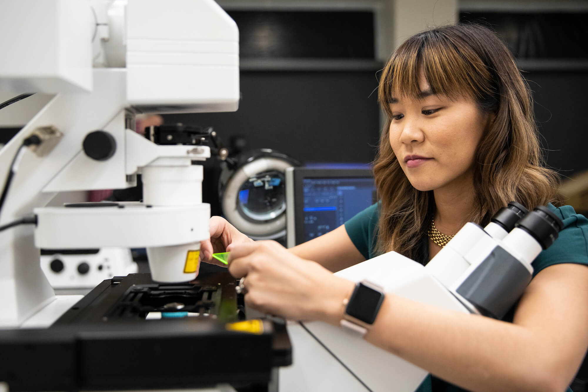 A scientist works with a microscope in a lab.