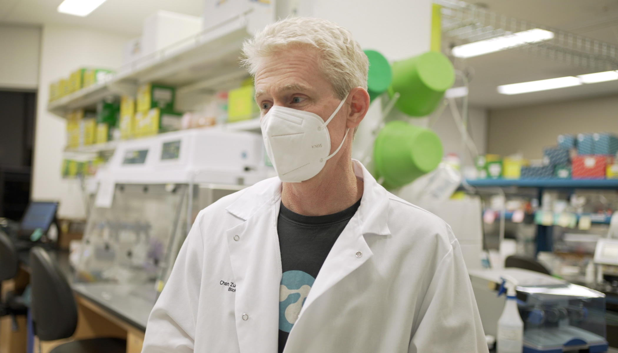 Joe DeRisi in white lab coat wears a N-95 mask in a COVID-19 lab.