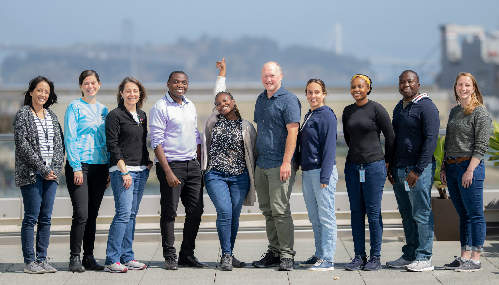 A group of 10 individuals faces a camera, smiling. The Golden Gate Bridge in San Francisco, California, is in the blurred background.