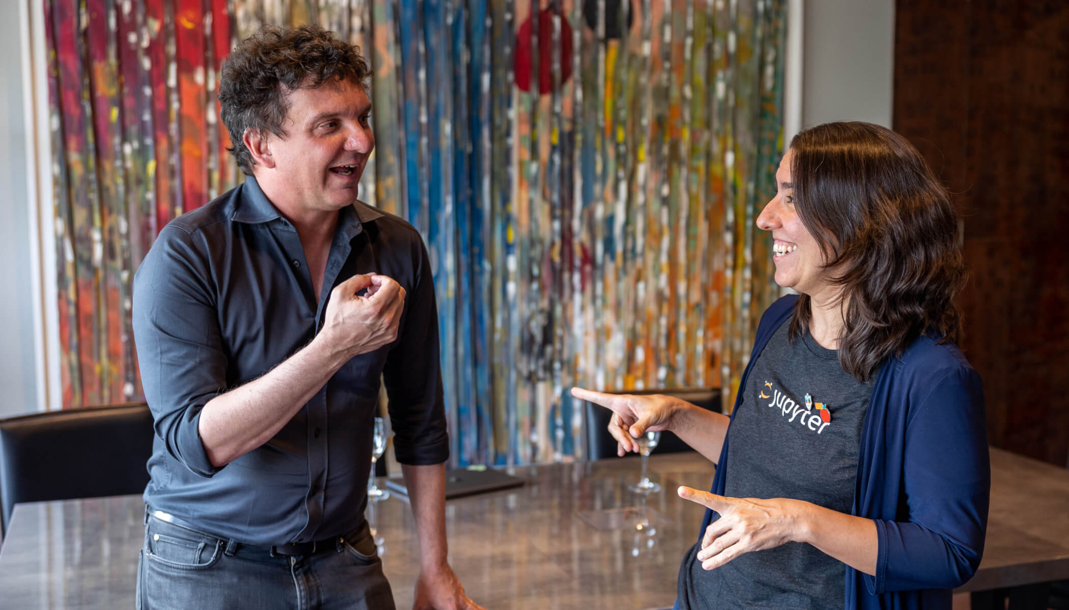 Dario Taraborelli and Laura Ación have a conversation. A sparkly, multi-colored backdrop is behind them.