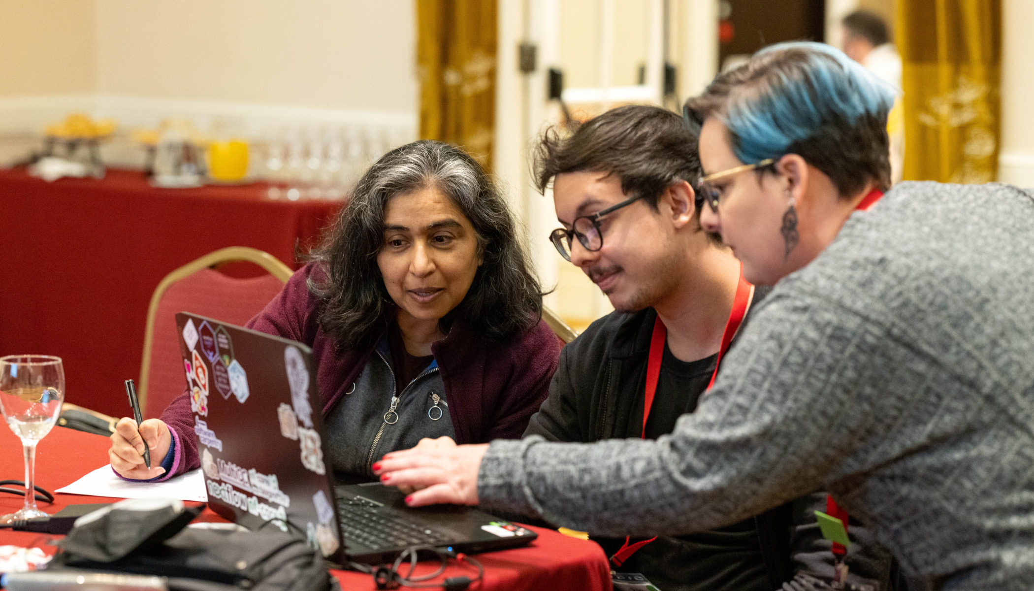 Three people look at a laptop.