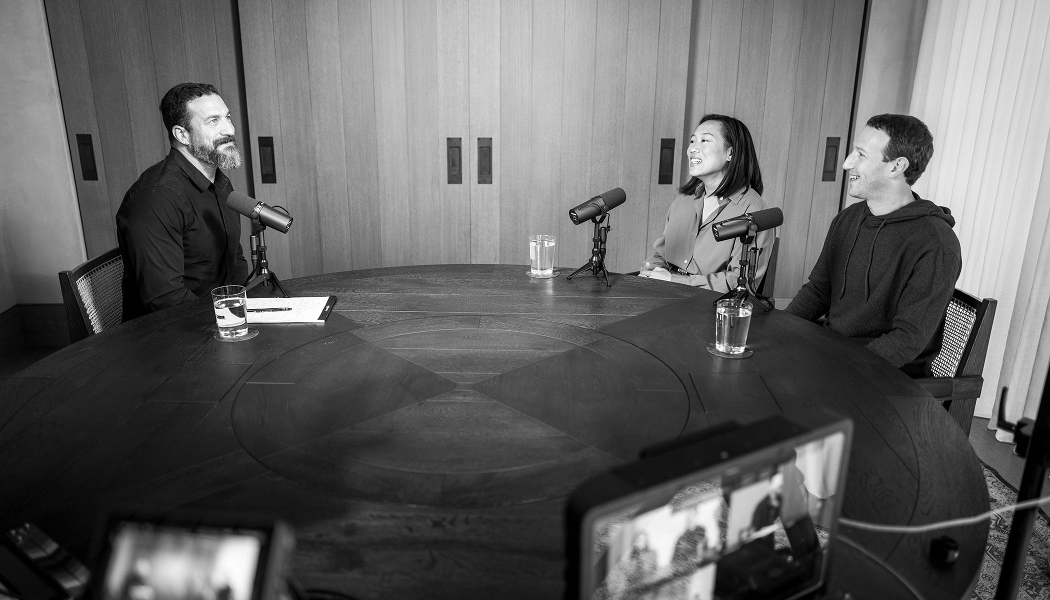 Andrew Huberman sits across a table from Priscilla Chan and Mark Zuckerberg. All three speak to each other and into microphones.