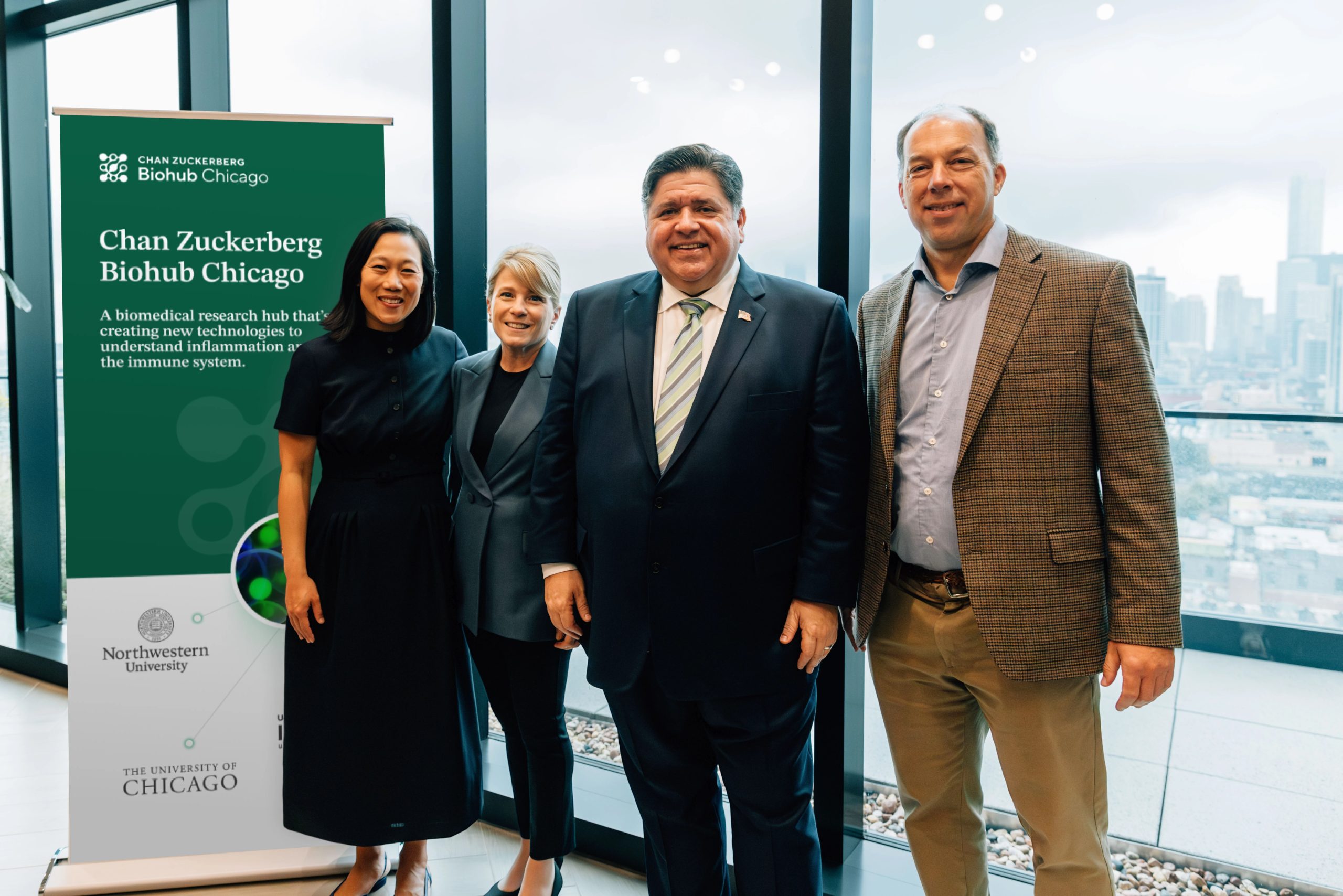Four people standing together in front of a banner.