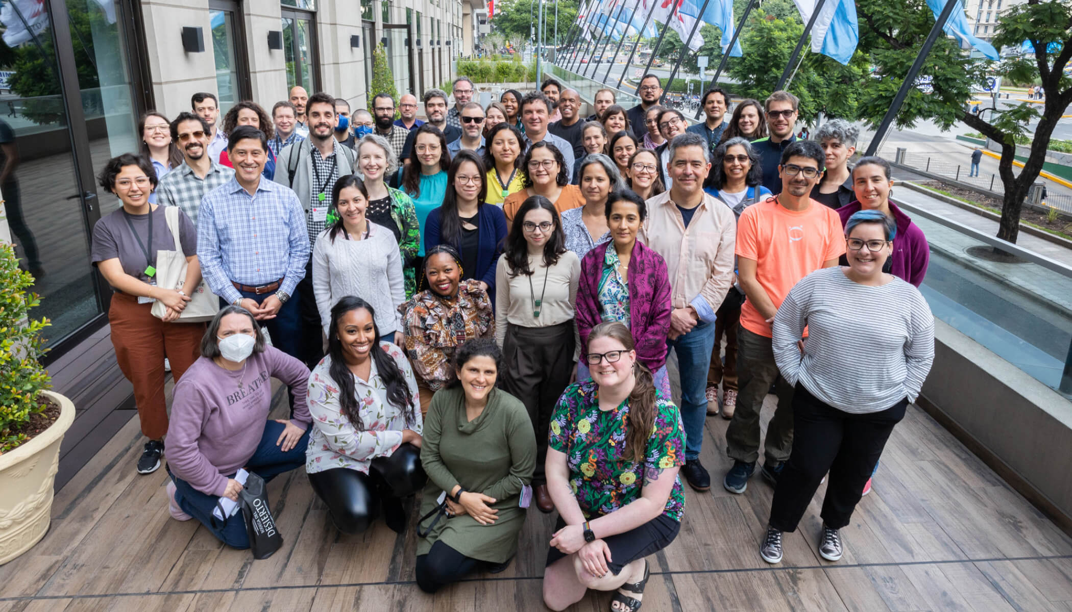 A group of fifty people gathers on a balcony outdoors.